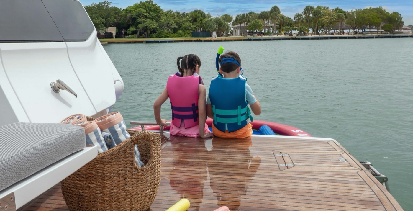 Two children in life vests sitting on the swim platform