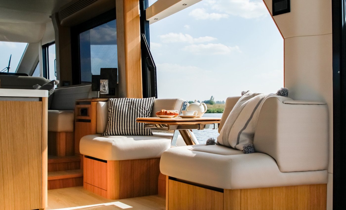 Sunlit saloon lounge with floor-to-ceiling glazing over the water