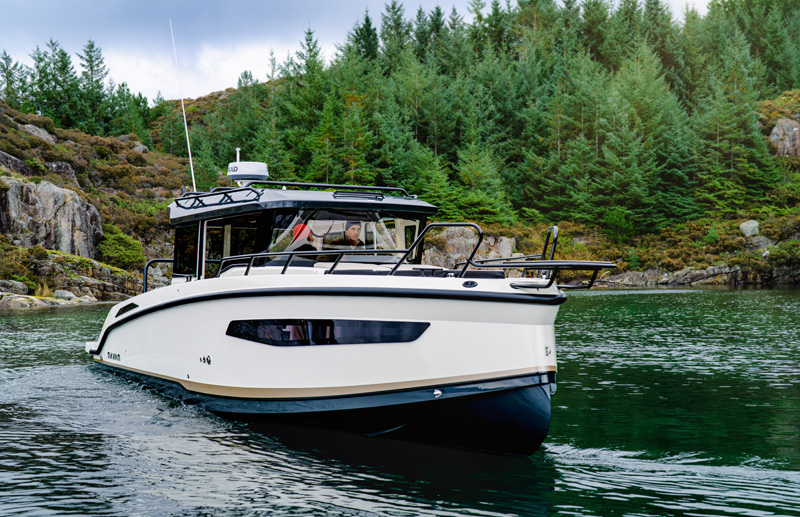 Navan C30 bow view at anchor off a rocky, forested shoreline
