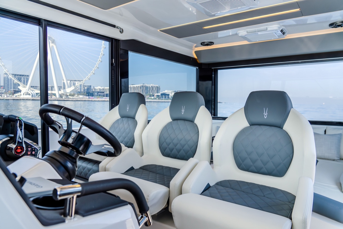 Oryx 47LX 格纹驾驶座椅与方向盘,舷窗外是海滨城市与摩天轮